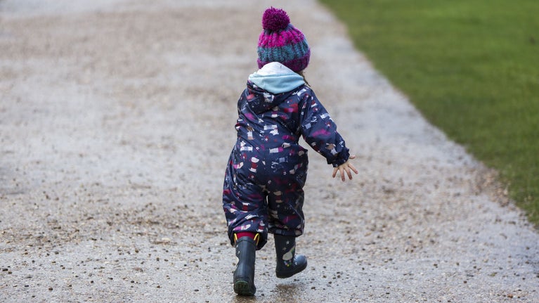A child in an all-weather suit running along a path